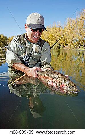 Stock Photo - Man holding a rainbow trout. Silver Creek, Idaho. USA. Fotosearch