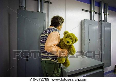 Man holding a stuffed animal as he stands in front of electrical panels at a factory. View Large Photo Image Stock Photo - Man holding a stuffed animal as he stands in front of electrical panels at a factory.. Fotosearch