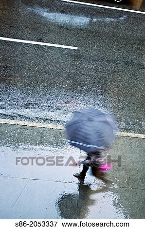 Stock Photo - Man Holding and Open Umbrella, Rushing Down a Rain Swept Street. n New York City. Fotosearch