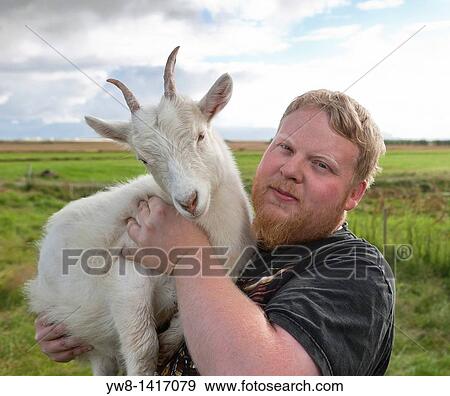 Stock Photo - Man holding billy goat, Iceland. Fotosearch