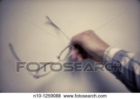 Stock Photo - Man holding his glasses in front of a classroom whiteboard. Fotosearch
