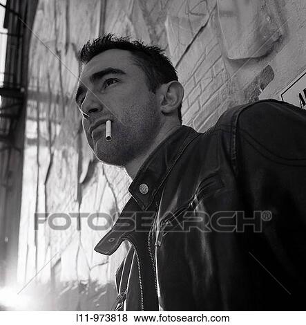 Stock Photo - Man in alley, smoking a cigarette. Fotosearch