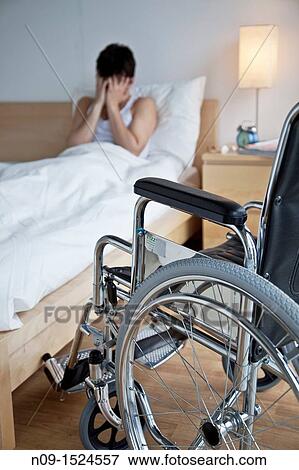 Stock Photo - Man in bed and wheelchair. Fotosearch