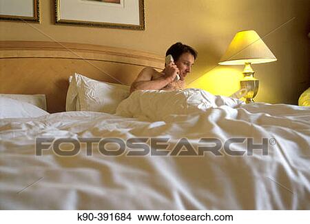 Man in bed holding a phone View Large Photo Image Picture - Man in bed holding a phone. Fotosearch