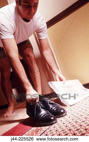 Man in boxers picking up polished shoes and newspaper from hotel room door View Large Photo Image Stock Photograph - Man in boxers picking up polished shoes and newspaper from hotel room door. Fotosearch