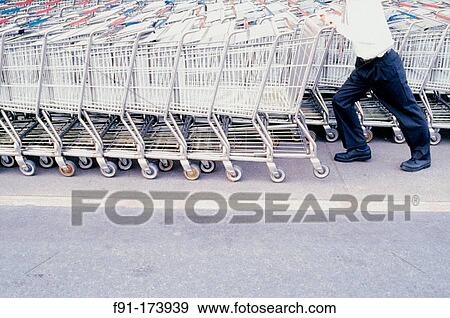 Man in business attire struggling to push a row of shopping carts View Large Photo Image Stock Photo - Man in business attire struggling to push a row of shopping carts. Fotosearch