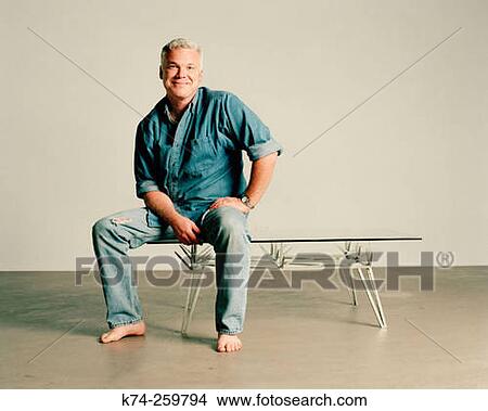 Picture - Man In Denim Shirt and Jeans Sitting On Table. Fotosearch