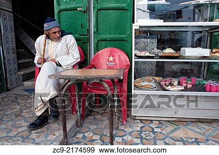 Man in djellaba sitting at a cakes shop terrace in the medina, Tetuan, Morocco. View Large Photo Image Stock Photo - Man in djellaba sitting at a cakes shop terrace in the medina, Tetuan, Morocco.. Fotosearch