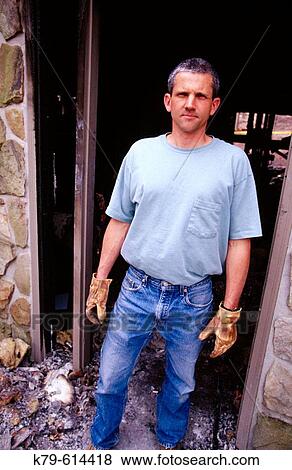 Stock Photo - Man in front of burned home. Fotosearch