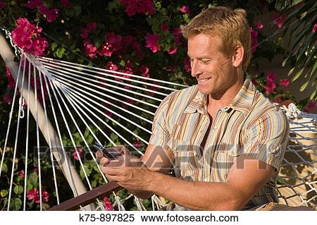 Man in hammock with cell phone View Large Photo Image Stock Photography - Man in hammock with cell phone. Fotosearch