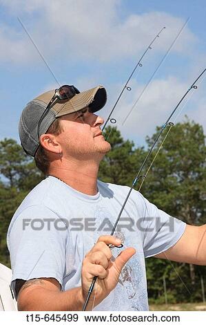Man in his 30's fixing fishing lines running multiple fishing rods at the same time View Large Photo Image Stock Photo - Man in his 30's fixing fishing lines running multiple fishing rods at the same time. Fotosearch
