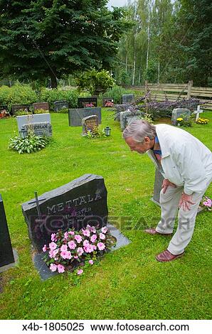 Stock Photography - Man in his 70s by the graveside of a relative at graveyard in Reposaari island Pori city Satakunta county western Finland Europe. Fotosearch