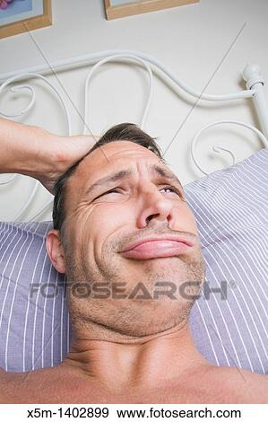 Stock Photo - Man in his bedroom waking up and scratching his head. Fotosearch