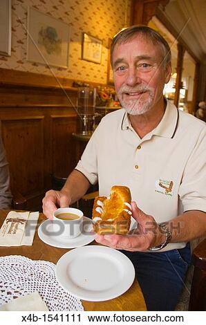 Stock Image - Man in his early 70s having coffee and cake Finland Europe. Fotosearch
