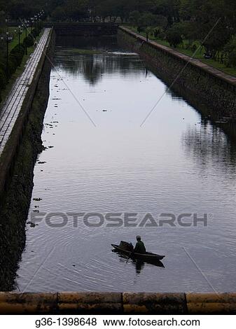 Man in in boat in the moat around the Imperial Palace in Hue, Vietnam View Large Photo Image Stock Photo - Man in in boat in the moat around the Imperial Palace in Hue, Vietnam. Fotosearch