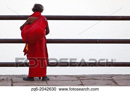 Man in red Frock looking onto the River Ganges in Varanasi, India View Large Photo Image Stock Image - Man in red Frock looking onto the River Ganges in Varanasi, India. Fotosearch
