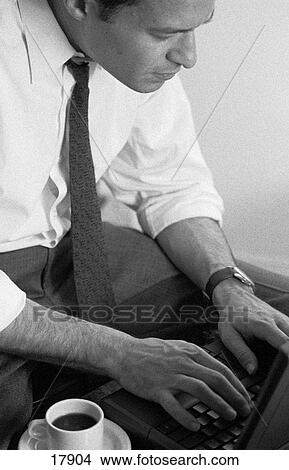 Picture - Man in shirtsleeves on laptop with coffee cup. Fotosearch