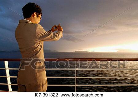 Stock Image - Man in suit taking picture from cruise ship. Alaska. USA. Fotosearch