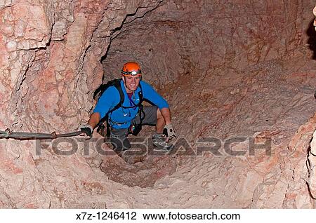Stock Image - Man in the tunnel while climbing the Giovanni Lipella via ferrata on Tofana De Rozes in the Dolomite Mountains near the city of Cortina in northern Italy. Fotosearch