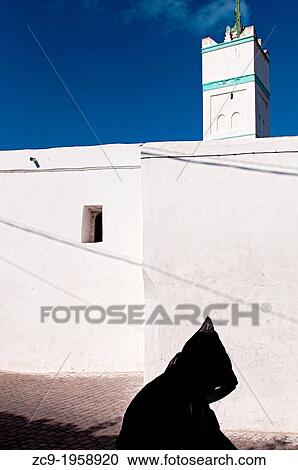 Man in traditional djellaba passing by a mosque in Azemmour medina, Morocco. View Large Photo Image Stock Image - Man in traditional djellaba passing by a mosque in Azemmour medina, Morocco.. Fotosearch