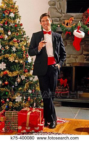 Stock Image - Man in tux by Christmas tree. Fotosearch