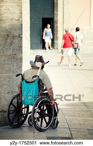 Stock Image - Man in wheelchair at the Cathedral of Valencia with cowboy hat, Spain. Fotosearch
