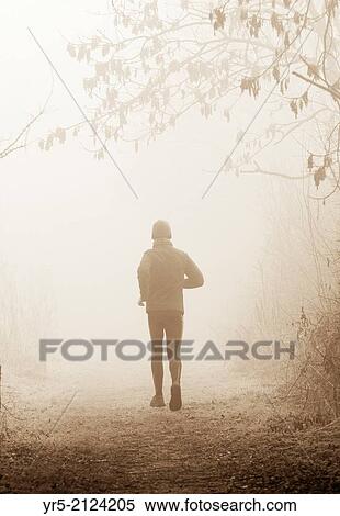 Man jogging in woodland park on a foggy day in winter. Billingham, north east England, United Kingdom. View Large Photo Image Stock Photography - Man jogging in woodland park on a foggy day in winter. Billingham, north east England, United Kingdom.. Fotosearch