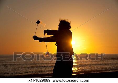 Man juggling with flaming poi at sunset View Large Photo Image Stock Photo - Man juggling with flaming poi at sunset. Fotosearch