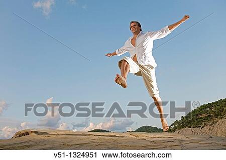 Man jumping in a cliff in Ibiza View Large Photo Image Stock Image - Man jumping in a cliff in Ibiza. Fotosearch