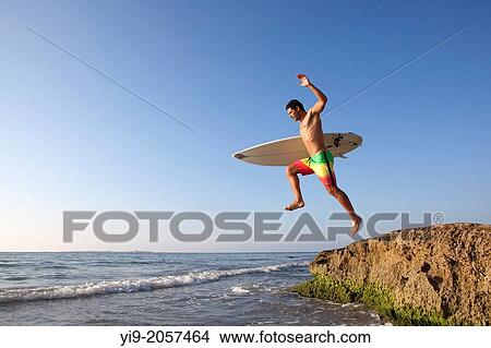 Man jumping into the water with his surf board. View Large Photo Image Picture - Man jumping into the water with his surf board.. Fotosearch