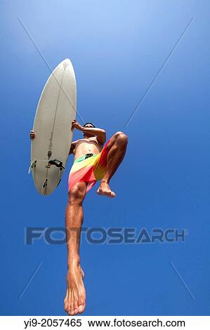 Stock Photography - Man jumping with his surf board.. Fotosearch