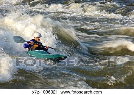 Stock Image - Man kayaking The Wave a rapid rated Class 4 on The Snake River near the town of Hagerman in southern Idaho USA. Fotosearch