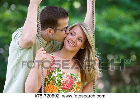 Man kisses girlfriend on a swing View Large Photo Image Stock Image - Man kisses girlfriend on a swing. Fotosearch