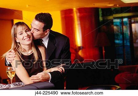 Man kissing woman on cheek in a bar View Large Photo Image Stock Image - Man kissing woman on cheek in a bar. Fotosearch