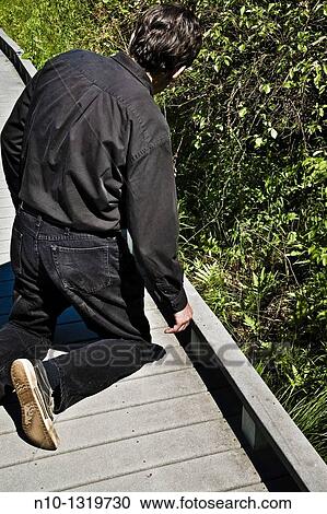 Man kneeling on a walking path at a park View Large Photo Image Stock Image - Man kneeling on a walking path at a park. Fotosearch