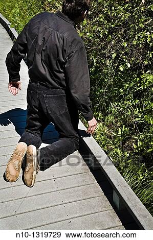Man kneeling on a walking path at a park View Large Photo Image Stock Photo - Man kneeling on a walking path at a park. Fotosearch