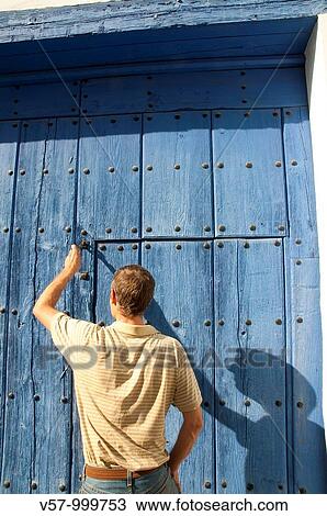 Stock Image - Man knocking at wooden door. Almagro, Ciudad Real province, Castilla La Mancha, Spain.. Fotosearch
