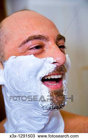 Stock Image - Man laughing with shaving cream on face. Fotosearch