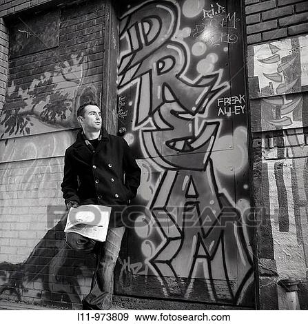Man leaning in alleyway with newspaper, looking off. View Large Photo Image Stock Photo - Man leaning in alleyway with newspaper, looking off.. Fotosearch
