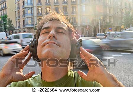 Man listening to music with headphones on a street. View Large Photo Image Picture - Man listening to music with headphones on a street.. Fotosearch