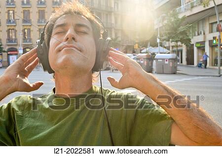 Man listening to music with headphones on a street. View Large Photo Image Stock Image - Man listening to music with headphones on a street.. Fotosearch