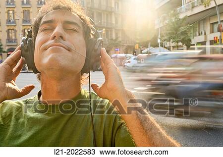 Man listening to music with headphones on a street. View Large Photo Image Stock Image - Man listening to music with headphones on a street.. Fotosearch