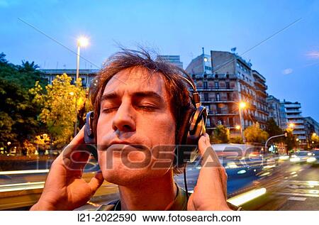 Man listening to music with headphones on a street. View Large Photo Image Stock Image - Man listening to music with headphones on a street.. Fotosearch