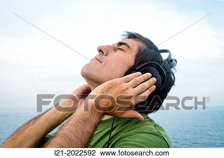 Man listening to music with headphones near the sea. View Large Photo Image Stock Image - Man listening to music with headphones near the sea.. Fotosearch