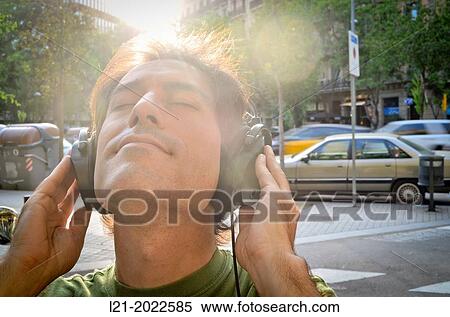 Man listening to music with headphones on a street. View Large Photo Image Stock Photography - Man listening to music with headphones on a street.. Fotosearch