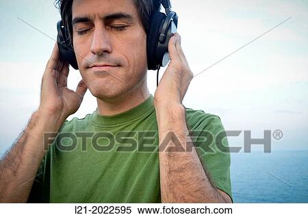 Man listening to music with headphones near the sea. View Large Photo Image Stock Photography - Man listening to music with headphones near the sea.. Fotosearch