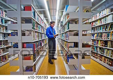 Man looking at books in a library View Large Photo Image Stock Image - Man looking at books in a library. Fotosearch