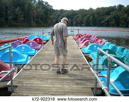 Man looking at recreational rental boats in park on lake. View Large Photo Image Stock Photo - Man looking at recreational rental boats in park on lake.. Fotosearch