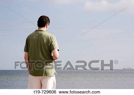 Man looking out over the Baltic as a cargo ship is passing by View Large Photo Image Stock Photograph - Man looking out over the Baltic as a cargo ship is passing by. Fotosearch