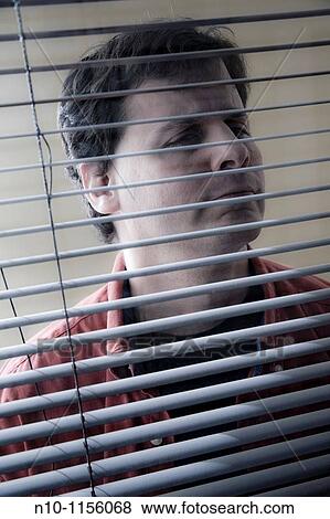 Man looking through his office window blinds View Large Photo Image Stock Photo - Man looking through his office window blinds. Fotosearch